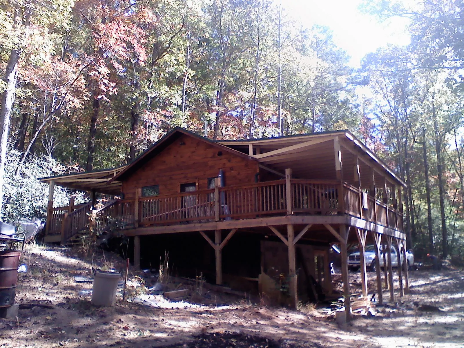 Log cabin with a wraparound porch and metal roof in the fall in Oakland